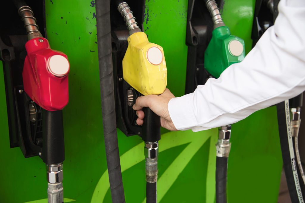 Estación de gasolina con una mano agarrando una manguera amarilla