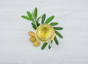 Olivas verdes y aceite de oliva en un frasco de vidrio con una rama de olivo desde vista aeria